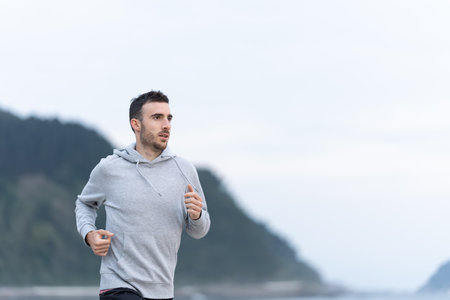 Sportsman wearing a hoodie running outdoors. Young man training with copy space in the sky.の写真素材