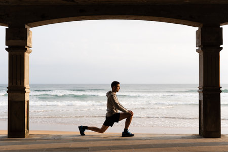 Young sportsman stretching legs outdoors before training at sunrise. Motivation and morning routine conceptの写真素材