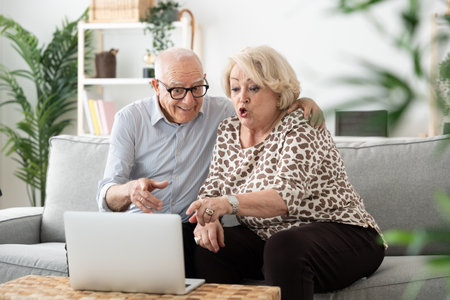Elderly couple having video call on laptop. Mature senior man and woman using technologyの写真素材