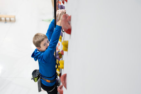 Preteen boy looking at camera while climbing with copy space. Active child practicing sport