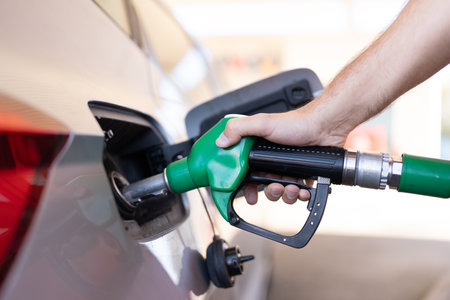 Closeup of hand refueling the car in a gas station. Unrecognizable person holding fuel nozzle and...