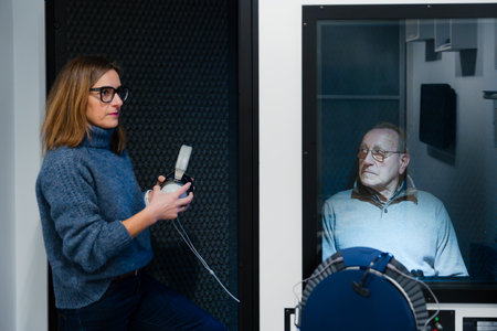 Audiologist holding headphones in a soundproof cubicle. Hearing loss concept