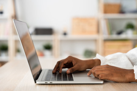 Closeup of unrecognisable black woman using laptop. Hands typing on keyboardの写真素材