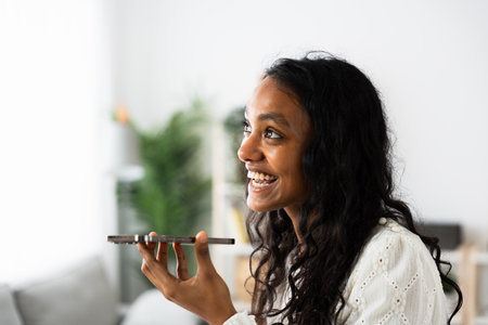 Indian teenager girl sending voice message. Positive young woman using phone.の写真素材
