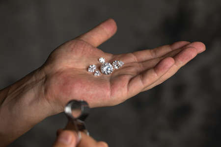 Large polished round cut diamond in hand close up front view. High quality photo