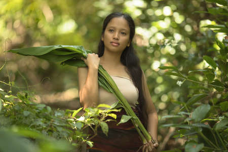 Portrait of Young beautiful asian woman with long hair in the jungle with banana leaves in hands...