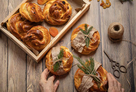 Homemade buns baked from yeast dough with raisins and dried apricots on wooden table top view. High...