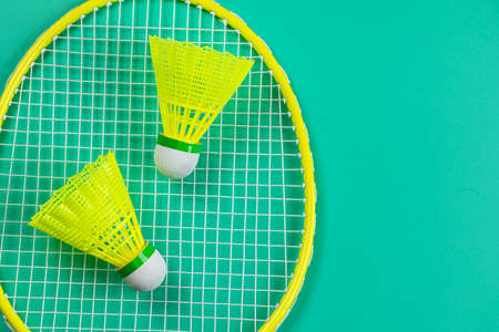 Yellow and red badminton rackets with shuttlecocks on bright green background top view flat lay. High quality photoの写真素材