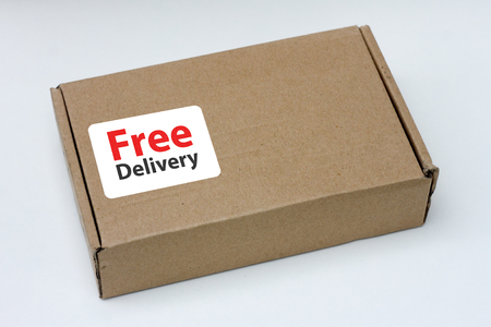 free delivery, business,online shopping, ecommerce and delivery service concept - brown box with note " free delivery " on a gray background. Flat lay, top view.の写真素材