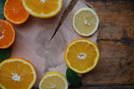 sliced oranges and tangerines with leaves on a wooden sawn, on a wooden backgroundの写真素材