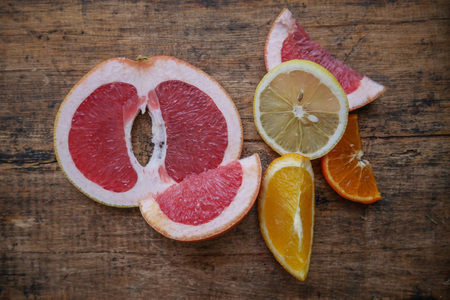 Fresh citrus fruits half cut on old wooden backgroundの写真素材
