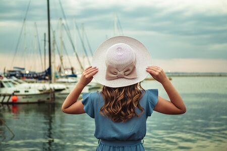 Happy traveler woman in yellow dress with hat enjoys the sea, fresh air on the beach.の写真素材