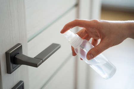 Coronavirus COVID-19 Prevention cleaning woman wiping doorknob with antibacterial disinfecting wipe for killing corona virus on touching surfaces or touching public bathroom handle with tissue.の写真素材