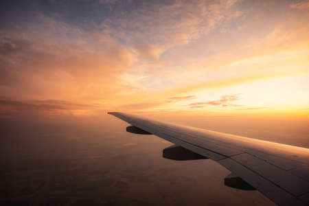 Flying high over endless fields Airplane wing and sunset. Long flight abroad.の写真素材