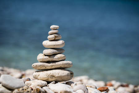 Balance pyramid of stones on the sea. Small pebble pillar. A symbol of calmness and tranquility.の写真素材