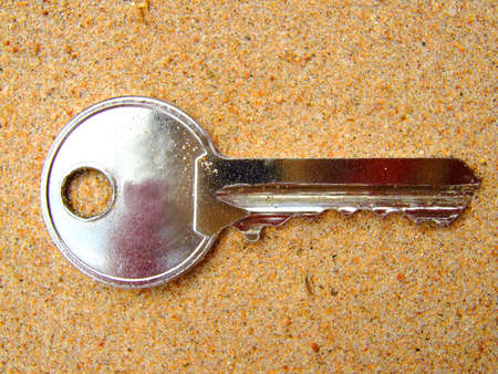 Photo of a key which lays on sand.の写真素材