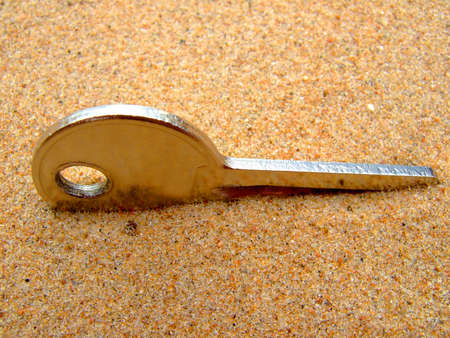 Photo of a key which will thrust in sand.の写真素材