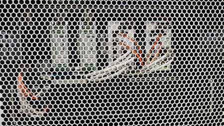 Close-up of automation equipment and network cables behind a protective metal grid in an industrial...
