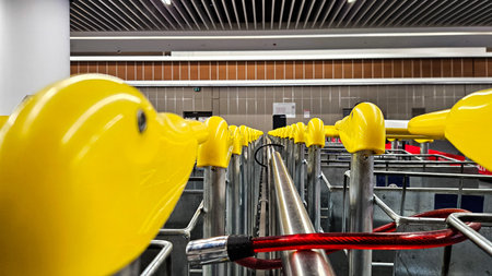 Row of yellow-handled luggage carts near baggage claim carousel in modern airport hall