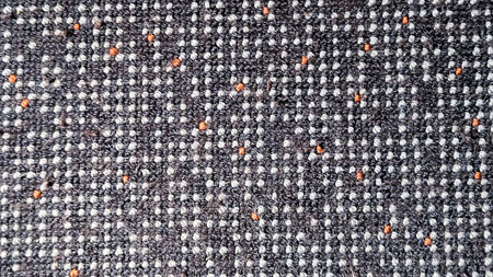 Close-up of fabric texture with grey pattern and orange dots