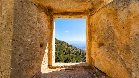 Distant mountain landscape framed by an ancient stone window creating a timeless travel concept...