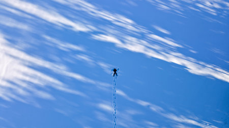 Solitary Skydiver Suspended Against Azure Sky, Braided Chute Line Trailing Downward, Soft Cloud...