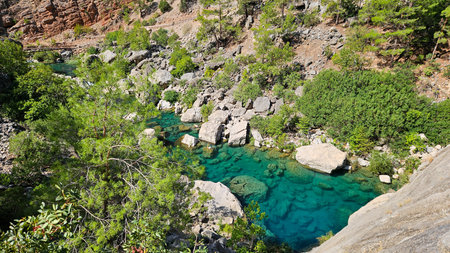 Turquoise Pool Nestled Among Boulders And Cliffside Vegetation, Crystal Clear Water Revealing Rocky Bottom, Tranquil Oasis Vibe With Lush Greeneryの写真素材