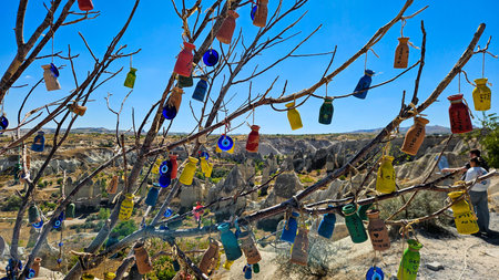 Colorful Bottles Hanging From Branches Against Rocky Plateau And Clear Blue Sky, Vibrant Glass Charms Tied With String, Closeup Detail, Festivallikeの写真素材
