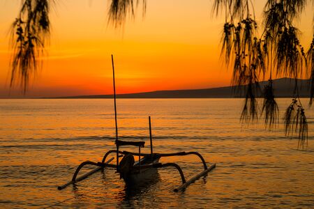 colorful Sunrise on the island in the ocean and a boat in the water, Indonesiaの写真素材