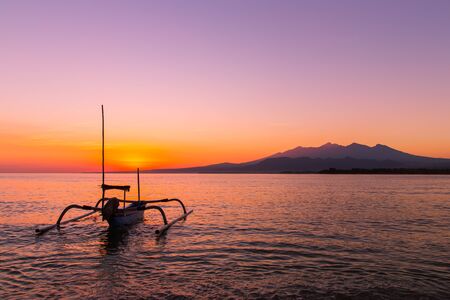 colorful Sunrise on the island in the ocean and a boat in the water, Indonesiaの写真素材