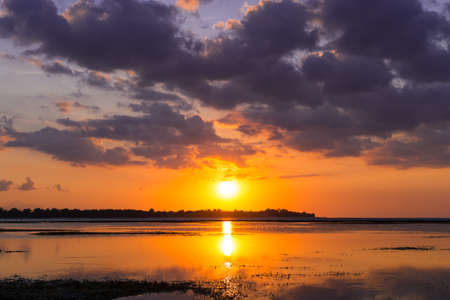 beautiful golden sunset on the beach through the haze with a golden sun track on water