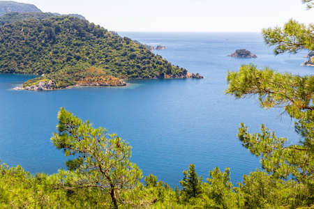view of the bay with blue water and the mountains with pine trees in the Mediterranean