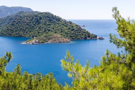 view of the bay with blue water and the mountains with pine trees in the Mediterraneanの写真素材