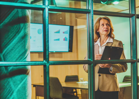 A middle-aged woman concentrates intently in a sophisticated office environment. Sheの素材