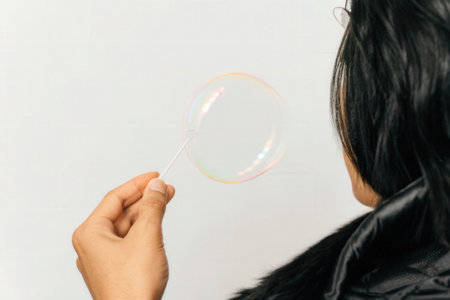 Young woman blowing soap bubble on white background, close-up viewの素材