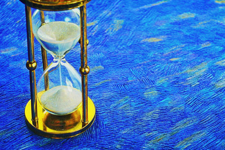 Vintage hourglass on blue background. Time is passing concept.の素材