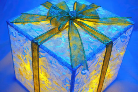 Gift box with yellow bow on blue background, closeup of photoの素材