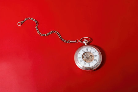 Vintage pocket watch on red background. Top view with copy spaceの素材