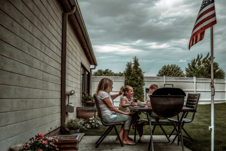 Three individuals enjoy a relaxed barbecue gathering in a residential backyard. The scene evokes a sense of family, community, and outdoor leisure, perfect for illustrating warmth and connection.の素材