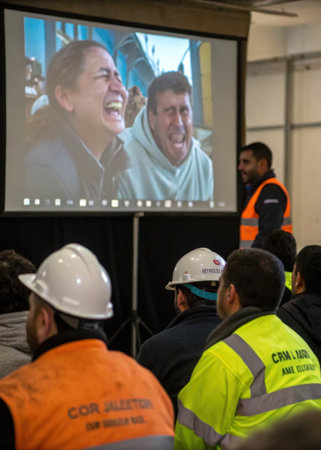 a group of people watching a man on a video screenの素材
