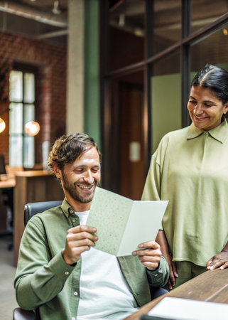 a man and woman sitting at a table with a laptopの素材