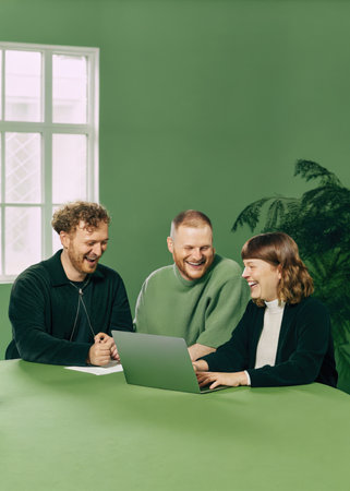 a man and woman sitting at a table with a laptopの素材