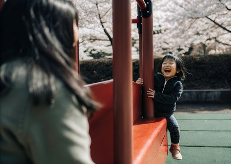 Asian mother and daughter playing in the playground at cherry blossom seasonの素材