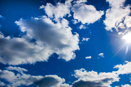 white clouds and sun rays in the blue sky
