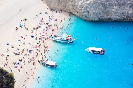 Full Navagio beach of people and three reantal boats, Shipwreck bay, Zakynthos island, Greece.