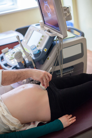 Pregnant woman checked by doctor in clinic. Focus on equipment.の写真素材