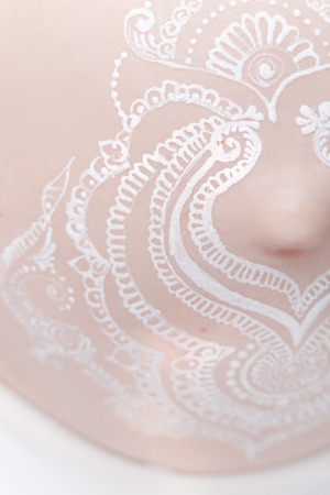 Pregnant belly closeup with white henna painting in boho style. High resolution.の写真素材