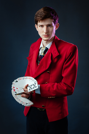 The magician in the red jacket does tricks with cards.の写真素材