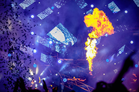 Fire show at the concert. Blue background, large screen monitor, confetti.
