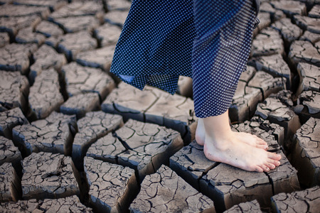 Heat shattered earth in the desert. Arid and sultry weather creates such beauty. Girl walks and stay on the cracked earth.の写真素材